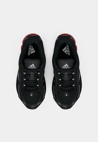 Crne Adidas tenisice s mrežastim gornjim dijelom, sivim naglascima i detaljem crvenog potplata. Imaju vezanje vezica i teksturiranu površinu.