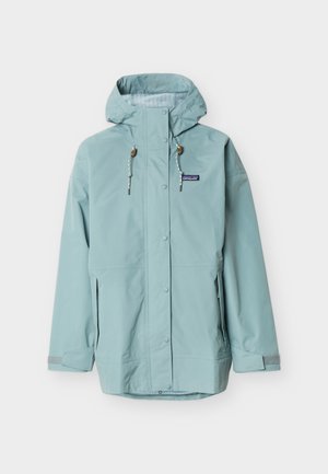 Ανοιχτό μπλε αδιάβροχο με κουκούλα, μπροστινά κουμπιά τύπου κλείσιμο με τυφλωτή, ρυθμιζόμενα κορδόνια, πλαϊνές τσέπες με φερμουάρ και ιμάντες καρπού με βέλκρο.