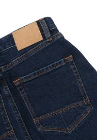 Jeans in denim blu scuro con tasca posteriore e cuciture arancioni, e un'etichetta in pelle color cuoio sulla vita.