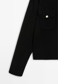 Maglione nero con orli e polsini a coste. Include una tasca frontale con un bottone argentato. Realizzato in un materiale morbido, presenta un design classico.