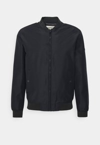 Blouson aviateur noir en tissu léger avec fermeture éclair à l'avant, poignets et taille côtelés. Comprend deux poches latérales et un design minimaliste.