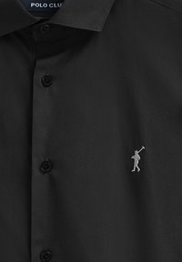 Camicia nera con bottoni, caratterizzata da un tessuto testurizzato, tre bottoni e una piccola figura ricamata in argento sul lato sinistro del petto.