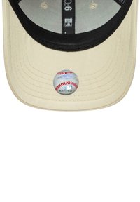 Beige Kappe mit einem schwarzen Schirm, die auf der Vorderseite einen holografischen Aufkleber eines Baseballs mit roten Nähten zeigt.