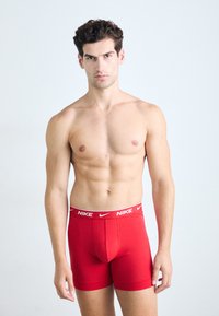 Rode Nike boxershorts met een witte gemerkte tailleband, van katoenen materiaal, rechthoekige vorm en een aansluitende stijl, gedragen door een mannelijke model.