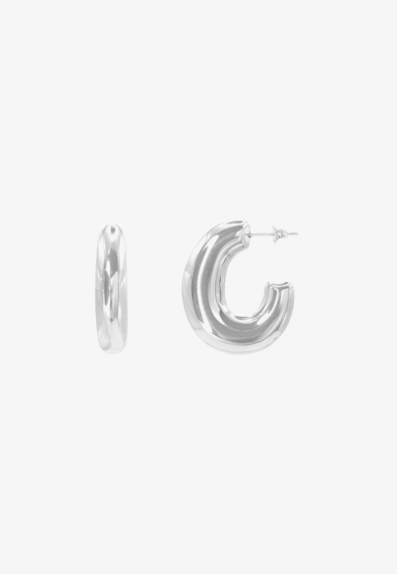 Boucles d'oreilles créoles épaisses en argent avec une surface brillante et arrondie ; une boucle montrée de côté, l'autre avec une tige et un fermoir visibles.