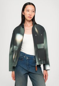 Lässig geschnittene Bomberjacke in Dunkelgrün mit abstraktem Druck; verfügt über zwei Fronttaschen, Metallknöpfe und ein kontrastierendes Taschen-Detail.