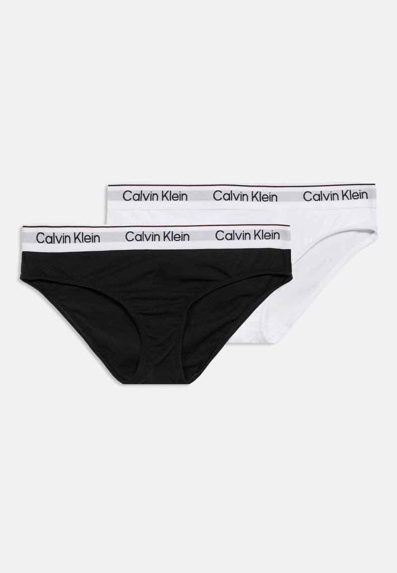 Δύο σλιπάκια Calvin Klein hipster σε μαύρο και άσπρο με ελαστικές μέσες με λογότυπο σε απλό φόντο.