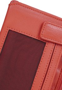 Červená kožená peněženka s texturovaným povrchem, která má síťovanou kapsu a kontrastní prošití. Obsahuje klopnu a akcentový zip.