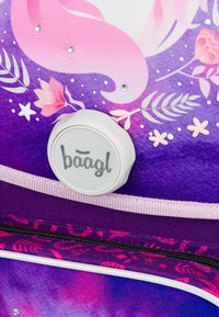 Fialový batoh s hravým designem zobrazujícím mořskou pannu, květiny a krystaly. Obsahuje detail v podobě kulatého loga a zipové zavření.