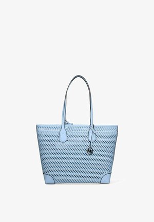 Borsa tote in tessuto azzurro chiaro con doppi spallacci e un piccolo pendente metallico rotondo appeso a una cinghia.
