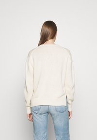 Cremfarbener, übergroßer Pullover aus weichem Strick. Mit gerippten Bündchen und Saum, runden Ausschnitt und gesenkten Schultern.