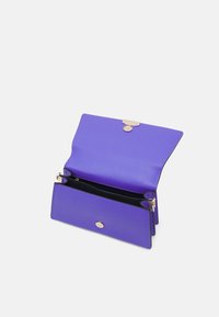 Fioletowy skórzany portfel z zapięciem na zatrzask, dwoma przegrodami oraz delikatnymi złotymi akcentami. Gładka tekstura z matowym wykończeniem.