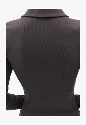 Sort ribbet stof top med krave, der har en tætsiddende design og lange ærmer, der fremhæver lodrette teksturdetaljer.