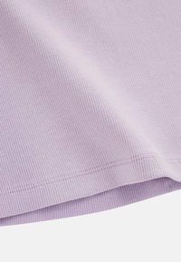 Tessuto ribaltato lilla, morbido al tatto, con un dettaglio a orlo piegato. Il tessuto presenta linee verticali derivanti dal motivo a coste.