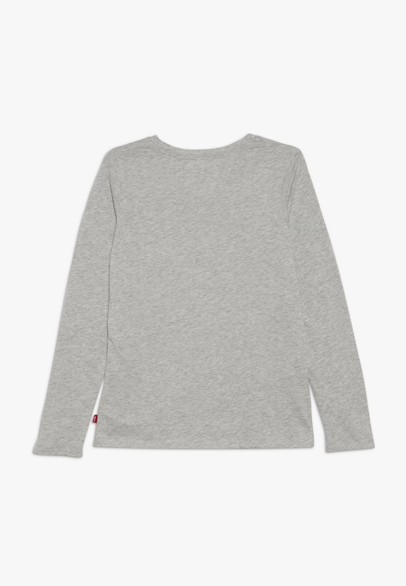 Camisa de manga larga gris claro con cuello redondo, vista desde la parte de atrás, mostrando una pequeña etiqueta roja en la costura lateral inferior.