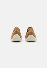 Braune Strick-Sneaker mit einem sockenähnlichen Obermaterial und weißen Gummisohlen. Sie verfügen über eine gerippte Textur und ein nahtloses Design ohne sichtbare Schnürsenkel.