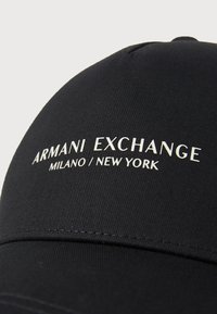 Black cap featuring embroidered "ARMANI EXCHANGE MILANO / NEW YORK" text. Smooth fabric with a structured, curved brim.