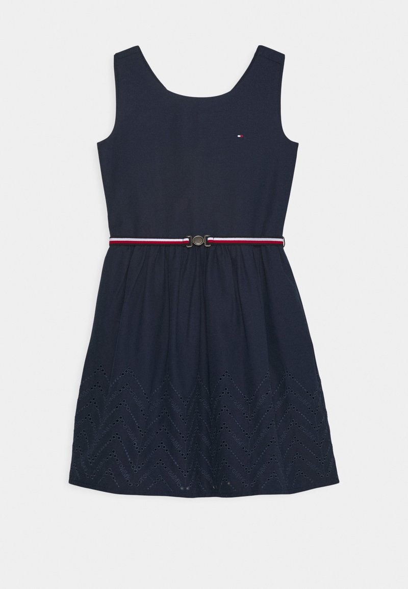 Vestido sin mangas azul marino con escote redondo, cintura ceñida con un cinturón de rayas rojas y blancas, y detalle de dobladillo en zigzag de ojales.