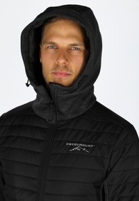 Giubbotto imbottito nero con cappuccio, caratterizzato da una chiusura con zip e un logo sul petto, realizzato in materiale liscio con dettagli testurizzati.