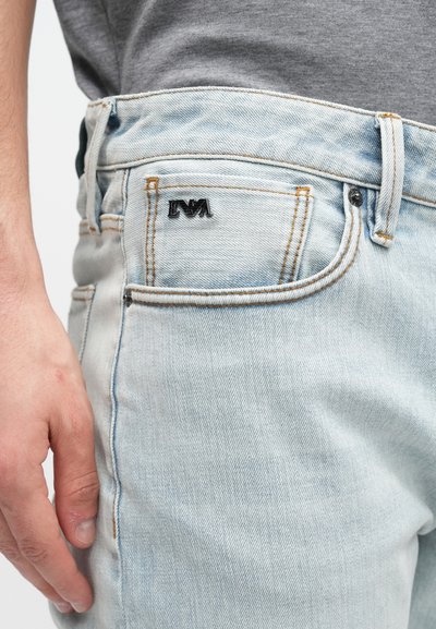 Φωτεινά μπλε τζιν από ντένιμ με στενή εφαρμογή, διαθέτουν ραφές σε αντίθεση, μαύρο λογότυπο στο πίσω τσεπάκι και κλασικό σχεδιασμό με πέντε τσέπες.