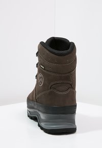Botas de caminhada castanhas com colarinho acolchoado, parte traseira estruturada e sola de borracha preta. Possui acabamentos em costura e material à prova d'água.