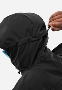 Veste à capuche noire en tissu lisse et texturé. Présente des cordons de serrage réglables sur la capuche et un col haut pour une protection supplémentaire.