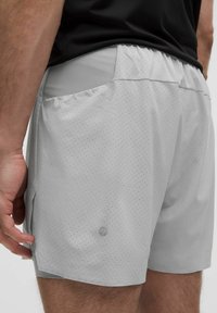 Hellgraue Sportshorts mit durchgehendem Perforationsmuster, elastischem Bund und einem Logo-Detail an der Seite.