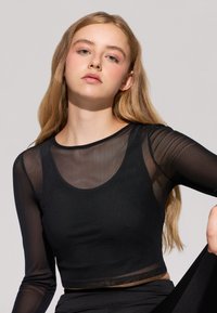 Czarny top z długim rękawem wykonany z przezroczystej siateczki, z dekoltem w kształcie łódki i skróconym krojem o dopasowanym fasonie.