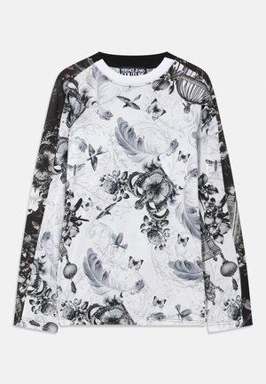 Garās piedurknes balta krekls ar melnām piedurknēm, rotāts ar pelēku toņu rakstiem, kas attēlo putnu spalvas, putnus, tauriņus, kronīšus un ziedu elementus.