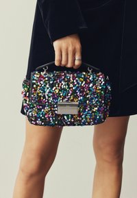 Svart handväska täckt med paljetter, med en mängd färgglada paljetter. Fyrkantig form med ett spänne i silver och en formad handled.