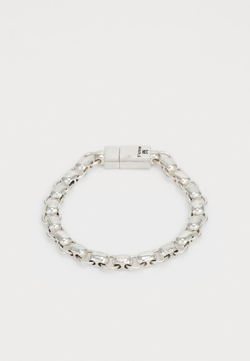 Sudraba ķēdes aproce ar pārmaiņus gludām un faktūrām taisnstūra saitēm, kā arī taisnstūra sprādzi, kurā iegravēts "MAPLE".