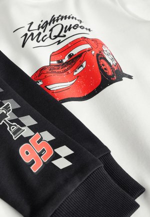 Biała bluza z nadrukiem czerwonego samochodu Lightning McQueen. Czarne rękawy z wzorami inspirowanymi wyścigami oraz czerwonym, pogrubionym numerem "95". Miękka w dotyku.