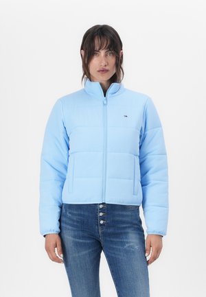 Lichtblauwe gewatteerde jas met een hoge kraag, voorrits en twee zijzakken. Draagt over donkere jeans, met een subtiele merklogo-detail.