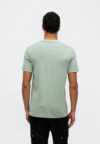 T-shirt de algodão verde menta de manga curta, com gola redonda e detalhes subtis nas costuras. Vista traseira lisa, sem padrões ou detalhes adicionais.
