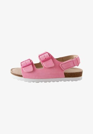 Różowy zamszowy sandał z dwiema regulowanymi klamrami na górze, paskiem na piętę, korkową wkładką i białą, karbowaną podeszwą.