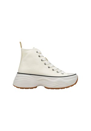 Zapatillas altas de lona blanca con una suela texturizada con patrón de ondas. Presenta ojales plateados, cordones blancos y una franja negra en contraste.
