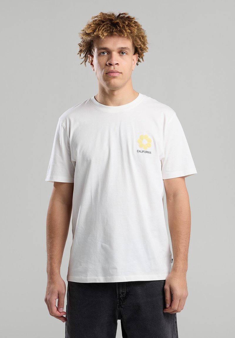 White cotton t-shirt featuring a yellow flower graphic with "CALIFORNIA" text on the chest. Short sleeves, round neckline, relaxed fit.
