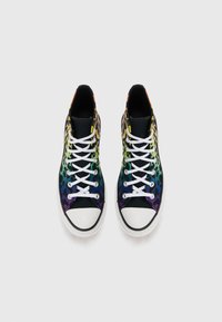 High-top sneakers with a multicolored leopard print in green, purple, and yellow; white laces and toe cap; black fabric background.