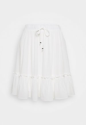 Biała spódnica do kolan z elastycznym paskiem w talii, sznurkiem do związania z koralikami oraz falbaną na dole.