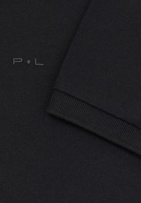 Czarna dzianina ma ribbowe wykończenie i subtelne logo "P.L" w matowym wykończeniu. Tekstura jest gładka i ma ścisły splot.