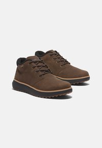 Zapatos de cuero marrón con acentos negros, puntera redonda, cordones, superficie texturizada y suela de goma con tacos para tracción.