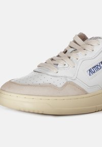 Sneaker bianca con dettagli in suede beige, tomaia in pelle perforata, punta rotonda, lacci piatti e suola in gomma texture crema.