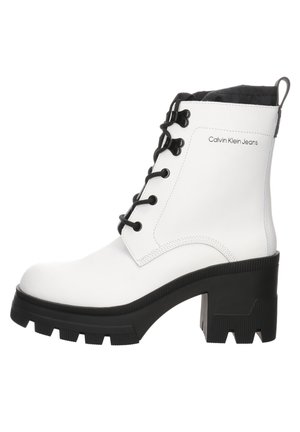 Weißer mittelhoher Calvin Klein Jeans Stiefel mit schwarzem klobigem Absatz, schwarzen Schnürsenkeln und robuster Sohle, Seitenansicht vor weißem Hintergrund.