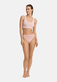 Set bikini rosa chiaro composto da un reggiseno a bralette con schiena a vogatore e culotte a vita alta. Tessuto morbido e liscio con cuciture minime e un design aderente.