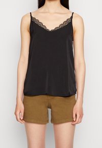 Camisole noire en satin, dotée d'un décolleté en V orné de dentelle délicate. Assortie à un short marron clair.