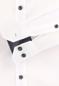 Biała koszula z czarnymi guzikami, z kontrastowym ciemnoniebieskim wzorem w kratkę wewnątrz mankietów oraz detalem guzikowym na rękawie.