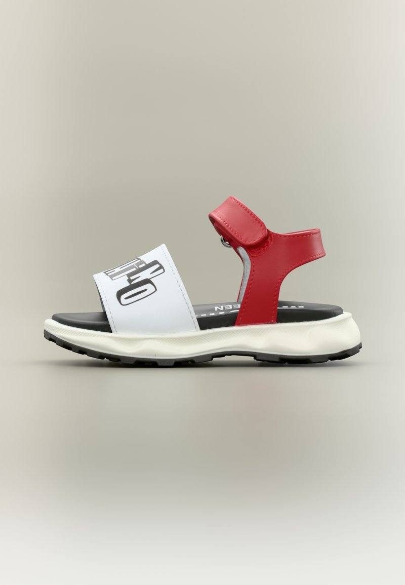 Κόκκινο και λευκό σανδάλι με ρυθμιζόμενο λουράκι, μαύρη σόλα και έντονο μαύρο κείμενο στο μπροστινό λουράκι.
