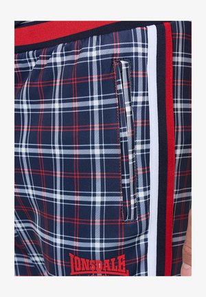 Mornarsko karirane kratke hlače z rdečimi in belimi poudarki, stranskim žepom na zadrgo in izrazitim logotipom na robu, narejene iz trpežne tkanine.