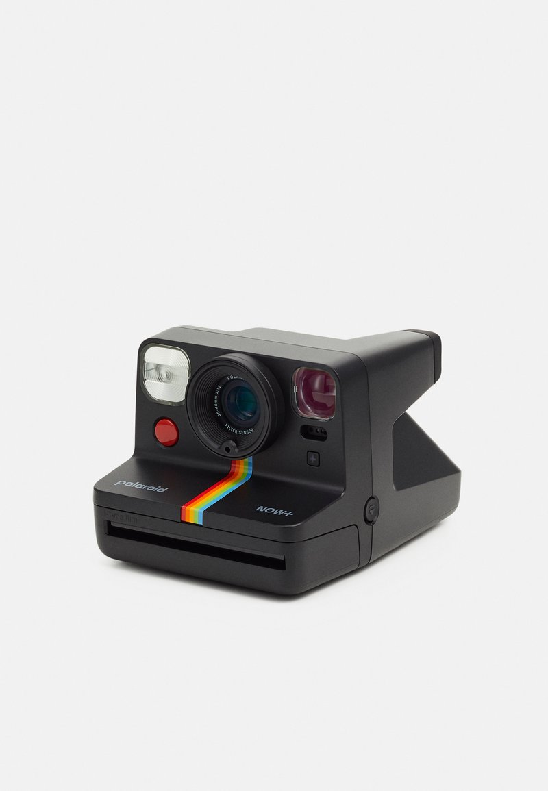 Polaroid NOW+ instant camera, matte black finish, circular lens, two buttons, flash, rainbow stripe, card slot at the bottom. Compact design.
