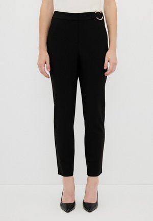 Black tailored pants with a slim fit, featuring a gold circle accent on the belt loop, smooth texture, and a cropped leg design.